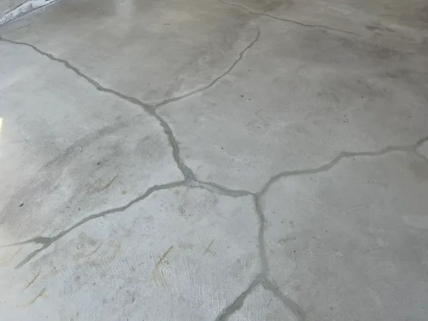 Cracked basement concrete floor with multiple radiating cracks before repair