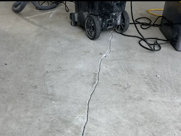 Basement floor crack with repair equipment staged for sealing