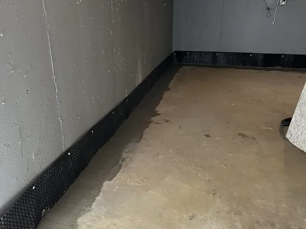 Interior basement waterproofing system with dimple board drainage channel along walls