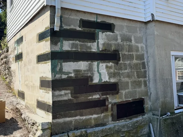 Concrete block foundation wall with carbon fiber reinforcement straps applied