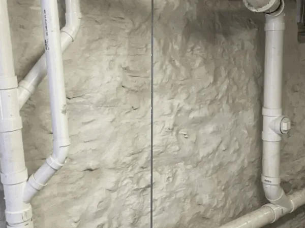 PVC drainage pipes installed on repointed stone foundation wall
