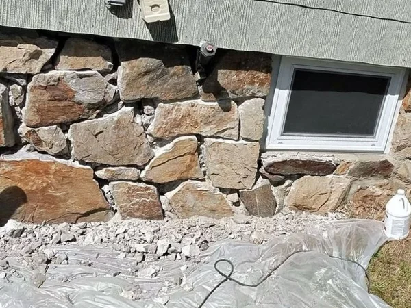 Stone foundation with crumbling mortar and gaps between stones before repointing